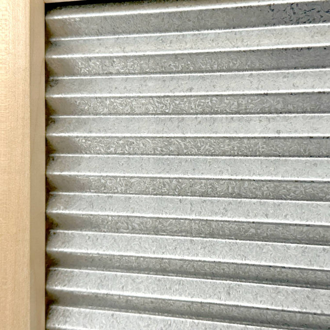 Close-up of a galvanized metal washboard with wavy ridges set in a mortised wooden frame, designed for effective stain removal, part of Laundry Supplies and USA Made collections.