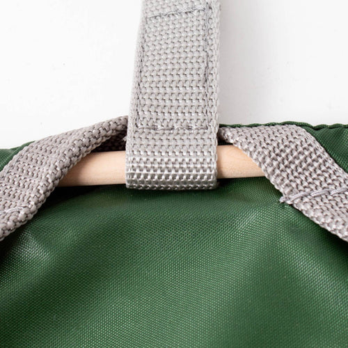Close-up of a green Amish clothespin bag featuring a sturdy gray strap with reinforced stitching clipped over a wooden dowel, handcrafted in the USA for Home & Decor and Laundry Supplies collections.