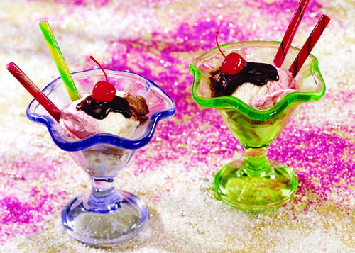 Two colorful glass dessert dishes filled with scoops of ice cream topped with chocolate syrup and maraschino cherries, surrounded by festive sprinkles for Kitchen & Food collections.
