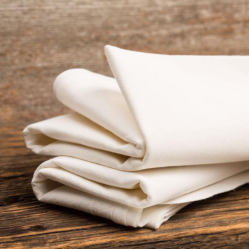 Stack of six neatly folded cream-colored flour sack kitchen towels made from soft, absorbent fabric, perfect for household cleaning and kitchen textiles in home and decor collections.
