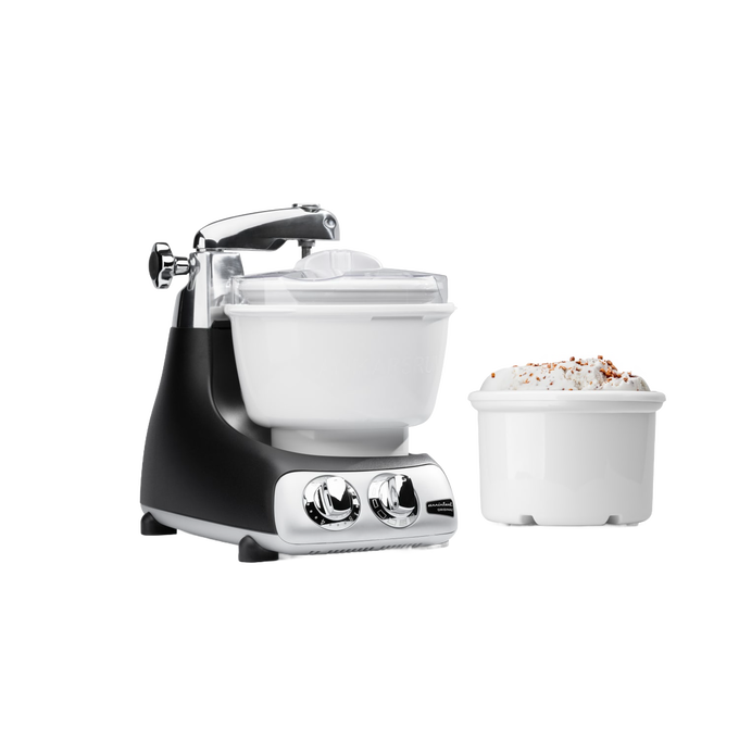 Black and silver ice cream mixer attachment with white freezing bowl and additional bowl filled with ice cream, designed as a specialty kitchen gadget for making frozen treats with ease.