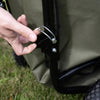 Close-up of a hand fastening a durable metal latch on the sturdy black steel frame with olive-green fabric liner of Lehman's Foldable Wheelbarrow & Firewood Cart, featured in Farm, Garden & Tool and Garden Accessories collections.