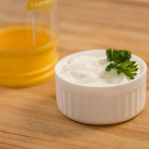 Small white ceramic ramekin filled with creamy homemade butter garnished with fresh parsley, set on a wooden surface with a measuring cup of melted butter nearby, perfect for Farm, Garden & Tool, Kitchen & Food, Specialty Equipment, Making Butter, Best Sellers, Homesteading, and Promo Eligible collections.