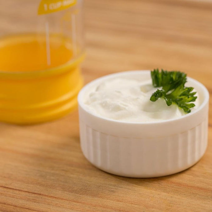 Small white ceramic ramekin filled with creamy homemade butter garnished with fresh parsley, set on a wooden surface with a measuring cup of melted butter nearby, perfect for Farm, Garden & Tool, Kitchen & Food, Specialty Equipment, Making Butter, Best Sellers, Homesteading, and Promo Eligible collections.