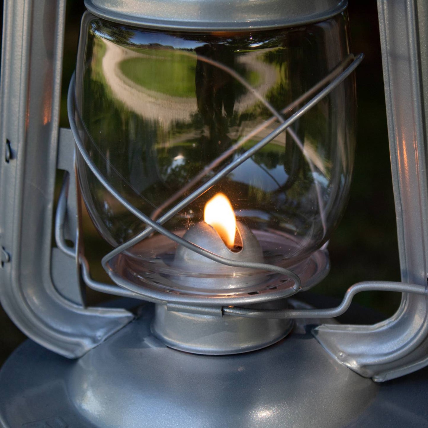 Close-up of a handcrafted lantern’s glass globe protecting a steady flame, showcasing durable metal construction ideal for camping, farm, emergency, and outdoor lighting needs.