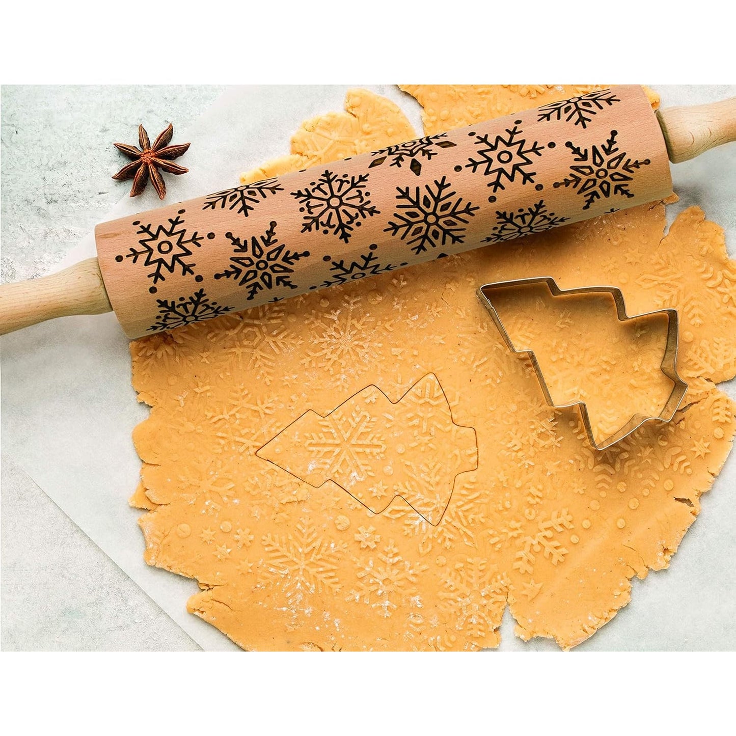 Beechwood rolling pin with detailed snowflake embossing pressing festive patterns into cookie dough beside a tree-shaped cutter, ideal for Kitchen & Food and Baking Supplies collections.