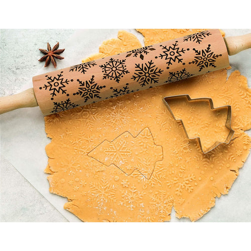 Beechwood rolling pin with detailed snowflake embossing pressing festive patterns into cookie dough beside a tree-shaped cutter, ideal for Kitchen & Food and Baking Supplies collections.
