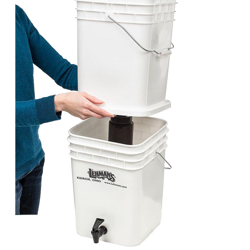 Person assembling a durable white two-bucket water filtration system with metal handles and spigot, designed for safe, large-volume water purification in farm, garden, emergency, and appliance use.