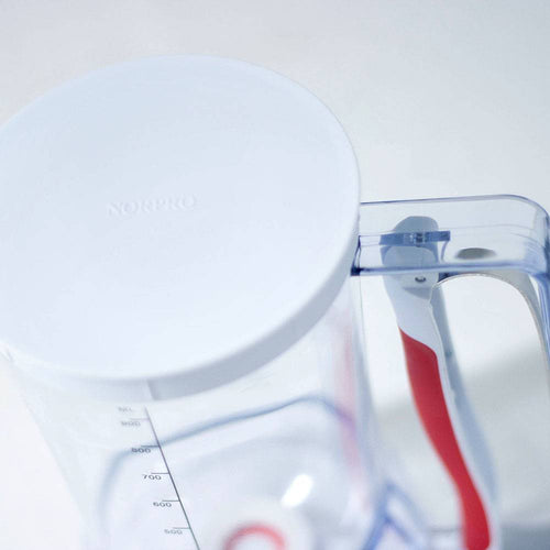 Transparent batter dispenser with soft red grip handle and white lid, marked with clear measurement lines, perfect for Kitchen Gadgets, Baking Helpers, and Best Sellers collections.