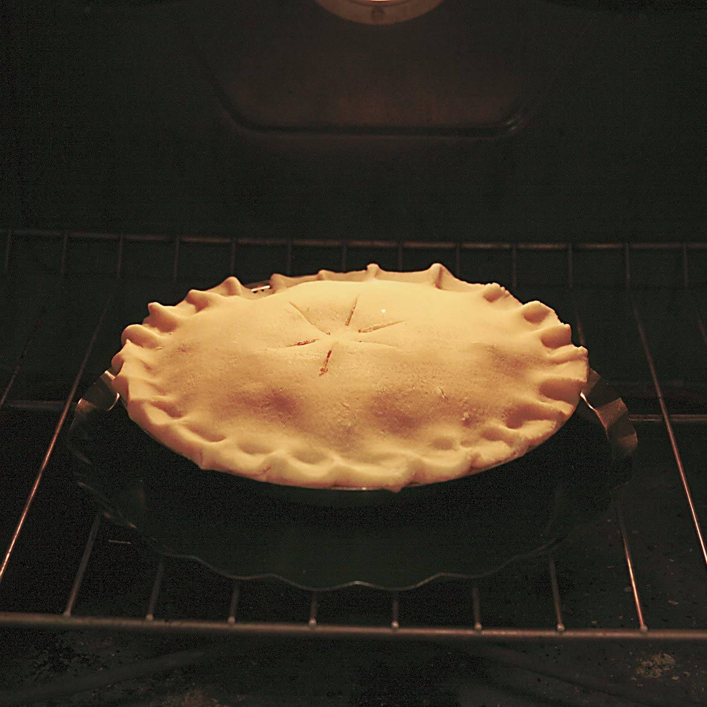 Fruit pie with a golden crust baking inside an oven, shown resting on a dark oven splatter guard with handles, suitable for Kitchen & Food, Kitchen Accessories, and Best Sellers collections.