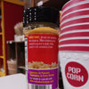 Plastic seasoning bottle with a black screw lid filled with yellow popcorn seasoning, featuring usage instructions and a colorful label, displayed near red and white striped popcorn containers, ideal for Kitchen & Food, Popcorn, USA Made, and Best Sellers collections.