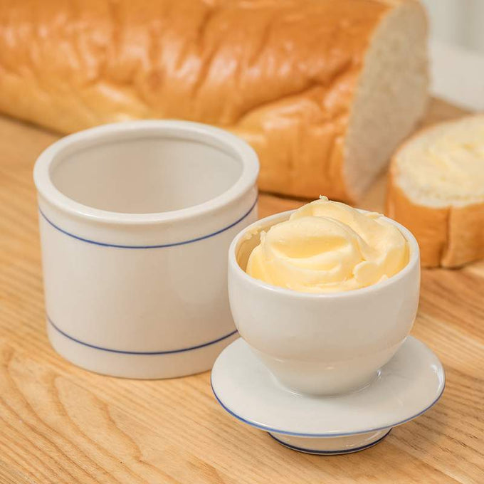Ancient-style ceramic butter crock with delicate blue line accents, holding soft whipped butter, set on a wooden surface with sliced bread, handcrafted and ideal for farm, kitchen, and homesteading use.