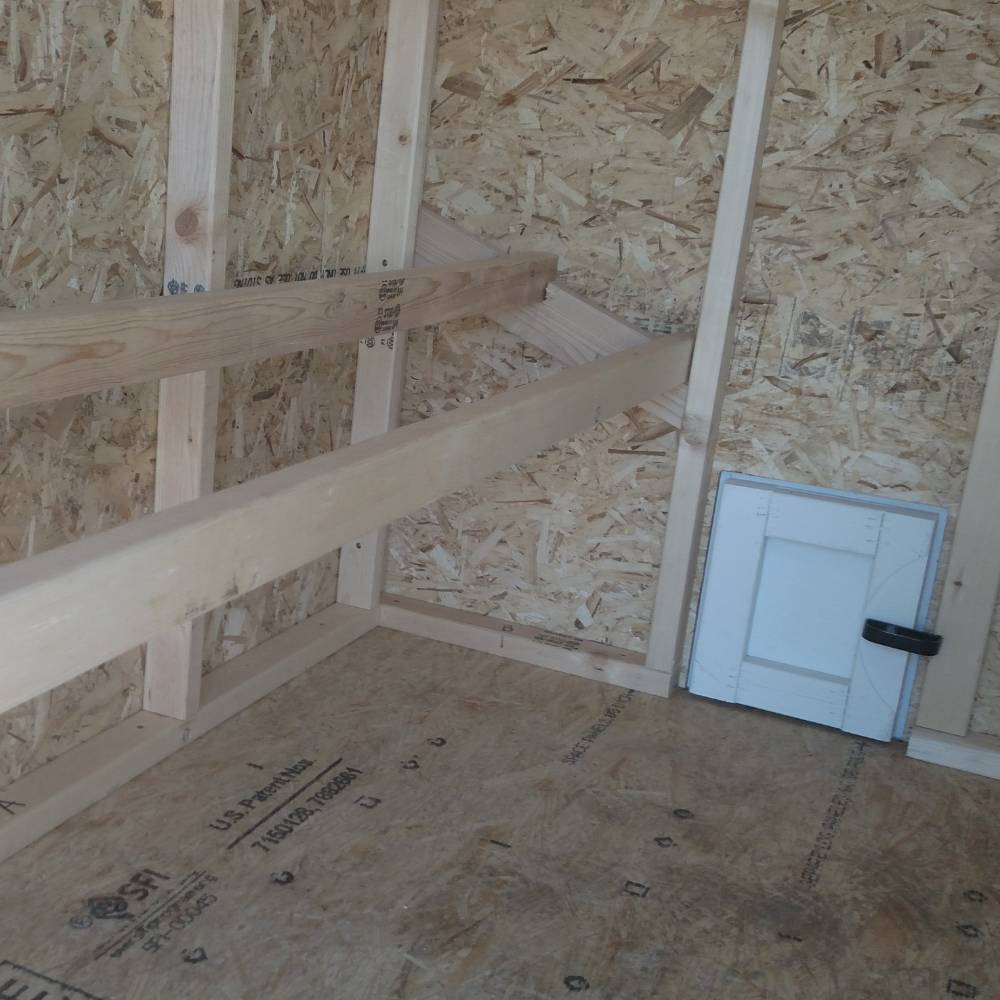Interior view of a handcrafted, heavy-duty wooden chicken coop made in USA, featuring natural wood framing, a small secure access door, and sturdy construction for farm and garden use.