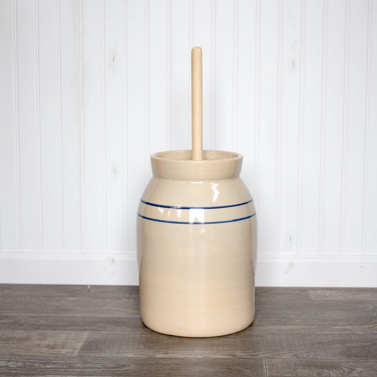 Handcrafted pottery butter churn in natural stone color with smooth-sanded wooden dasher and double blue stripe, made in USA, featured in Kitchen & Food and Specialty Equipment collections.