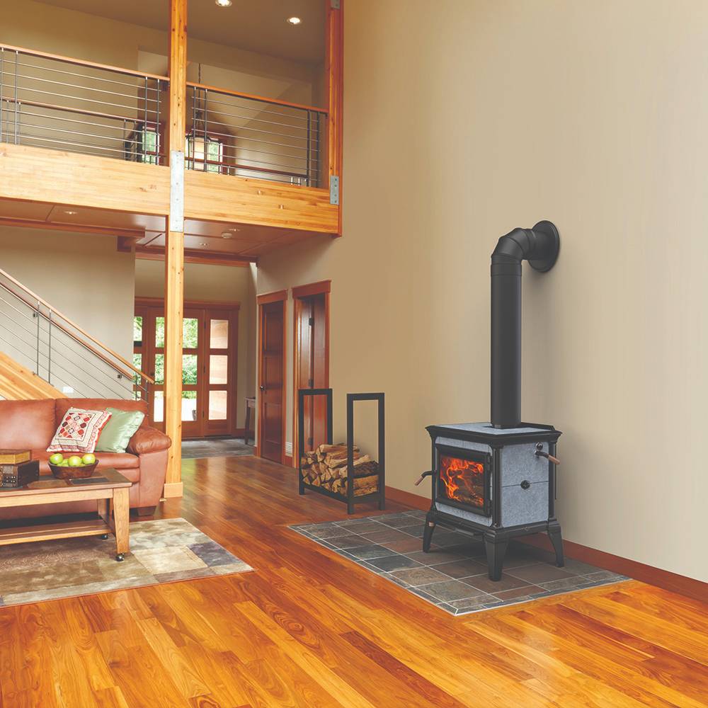 Modern wood heat stove with a visible burning fire, set on a tiled hearth in a warm living room with wooden floors and leather furniture, from Stoves and Heatstoves collections.