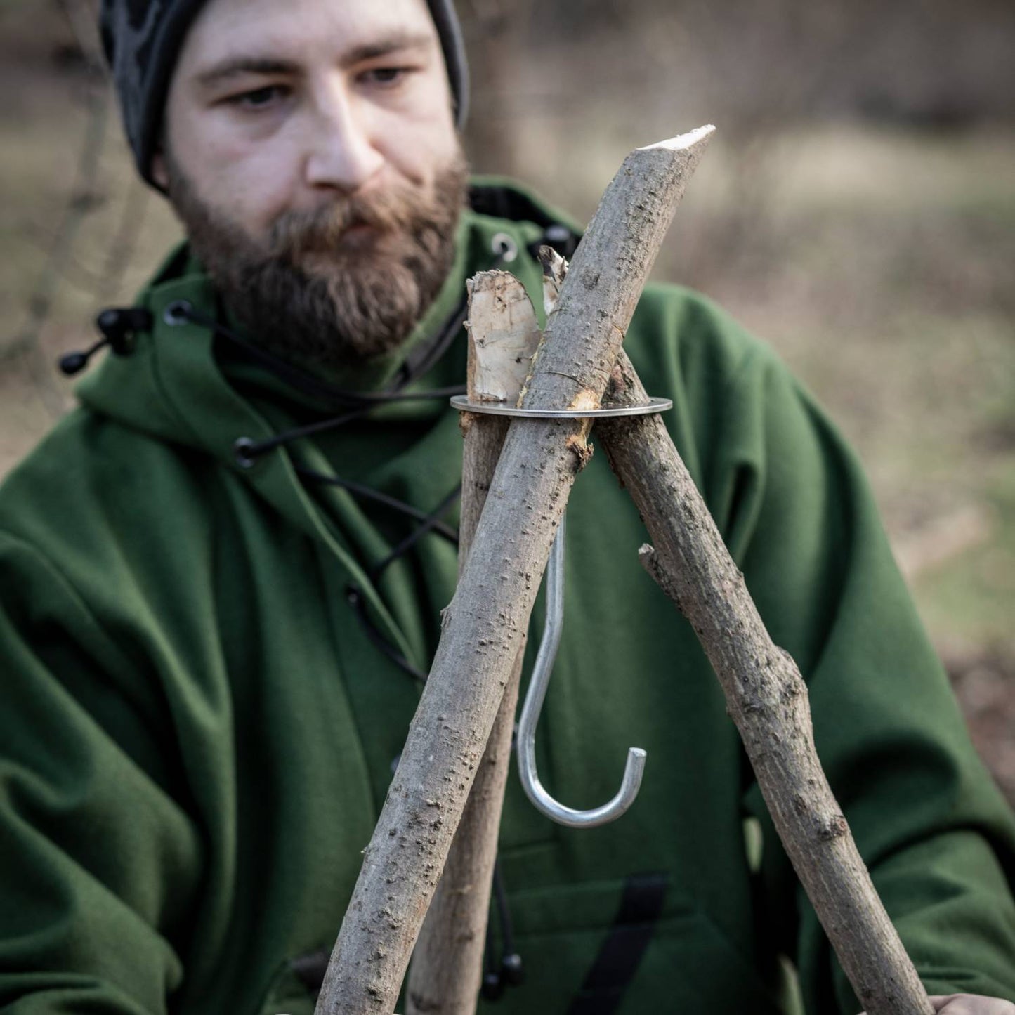 Man assembling a rustic branch tripod using a lightweight stainless steel lashing disc with attached hook and chain, ideal for outdoor cooking in Farm, Garden & Tool, Camping, Best Sellers, and Promo Eligible collections.