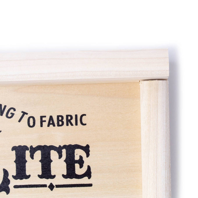 Close-up of the top corner of a handcrafted wooden frame with a decorative printed label on light wood, part of a handcrafted spiral washboard for laundry use in USA-made and best seller collections.