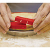 Hands placing a red silicone shield around a pie crust in a metal pie pan on a floured surface, designed to protect the crust while baking, featured in Kitchen & Food and Baking Supplies collections.