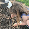 Young girl using a small hand tool to dig in garden mulch, demonstrating a compact planting trowel ideal for small hands, featured in Farm, Garden & Tool and Digging and Cultivating collections.