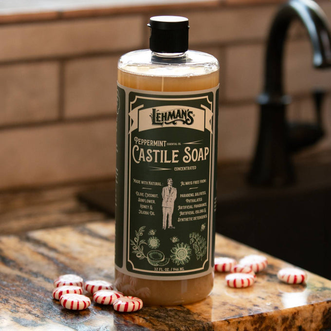 Clear bottle of Lehman's peppermint scented castile soap with green label, placed on kitchen counter near a faucet and peppermint candies, highlighting USA made natural soap for Health & Wellness, Grooming, and Soaps collections.