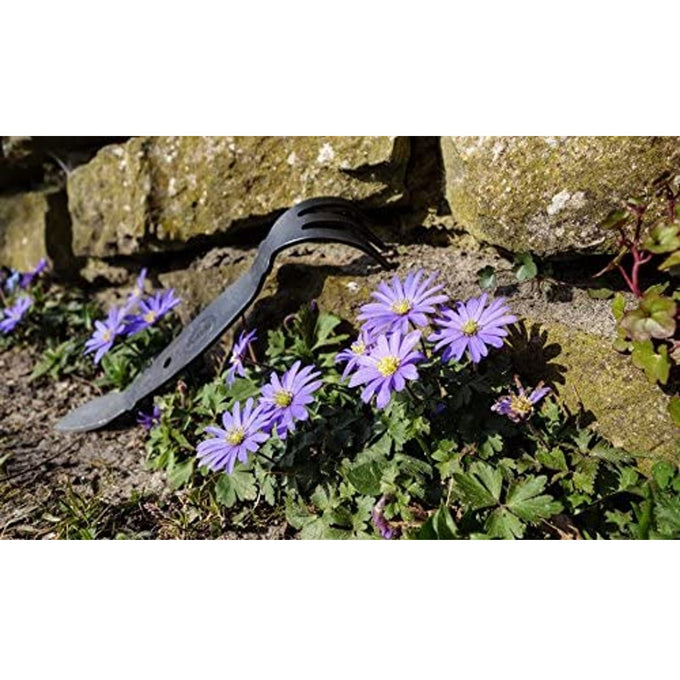 Handcrafted all-steel cultivator with a cobra-shaped head and three-pronged fork resting on soil near purple flowers and a stone wall, featured in Farm, Garden & Tool, Digging and Cultivating, Garden Accessories, Best Sellers, and Promo Eligible collections.