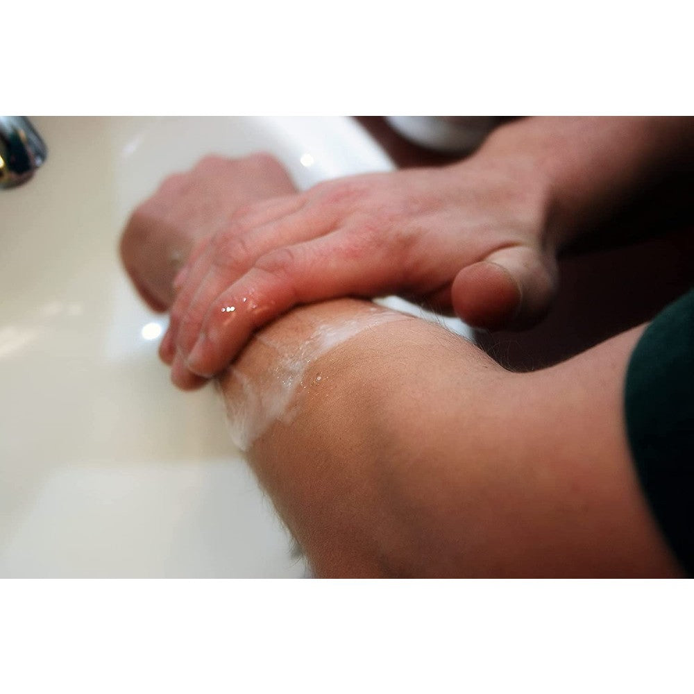 Person gently rubbing medicated scrub on forearm over a sink, demonstrating relief for poison ivy rash symptoms, featured in Health & Wellness, Health Remedies, USA Made, and Best Sellers collections.