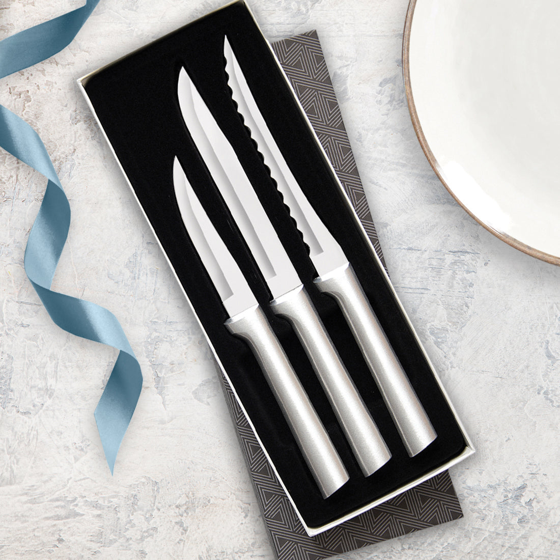 Three-piece set of handcrafted stainless steel knives with sleek silver handles, including heavy duty paring knife, utility steak knife, and serrated tomato slicer in a black gift box, USA made for kitchen and food prep collections.