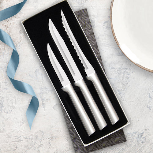 Three-piece set of handcrafted stainless steel knives with sleek silver handles, including heavy duty paring knife, utility steak knife, and serrated tomato slicer in a black gift box, USA made for kitchen and food prep collections.