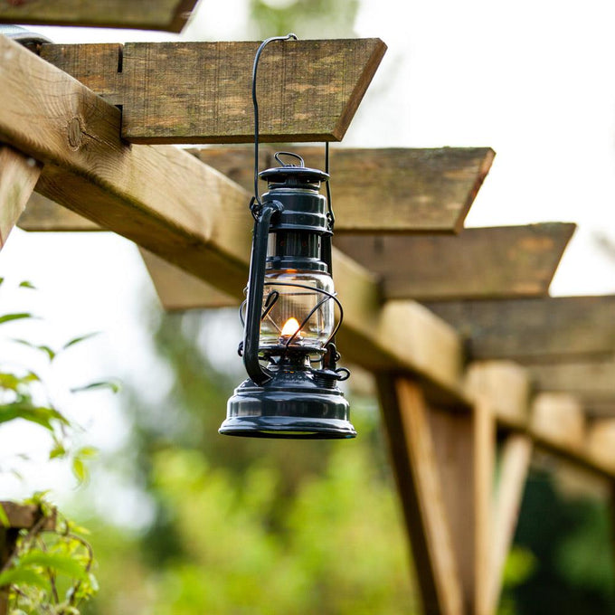 Handcrafted black galvanized oil lantern with thermal heat-resistant SUPRAX globe, hanging on a wooden pergola, ideal for lamps & lighting, camping, emergency supplies, and outdoor use.