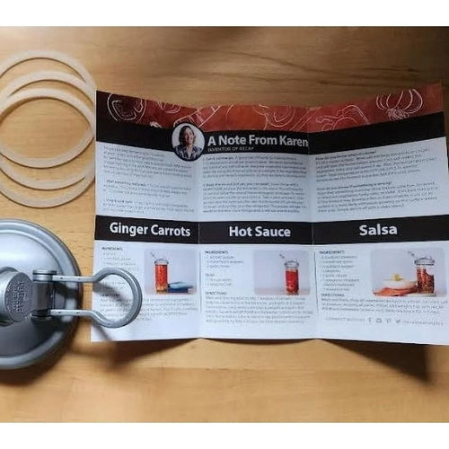 Instructional recipe guide for fermenting ginger carrots, hot sauce, and salsa displayed alongside a fermentation lid with metal clamp and silicone gaskets on a wooden surface, featured in Kitchen & Food, Food Preservation, Fermenting and Pickling, and USA Made collections.