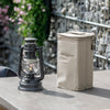 Beige nylon transport case with reinforced structure and zipper closure standing next to a lit vintage-style lantern, suited for camping, emergency supplies, and outdoor lighting.