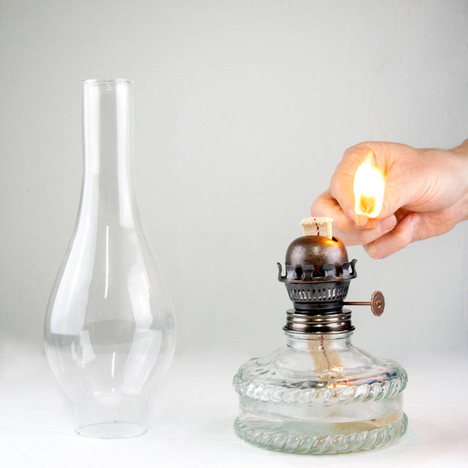Handcrafted reflector oil lamp with clear glass base, removable tall glass chimney, and adjustable wick knob being lit, ideal for Lamps & Lighting, Oil Lamps, Wall Lamps, Best Sellers, and Promo Eligible collections.