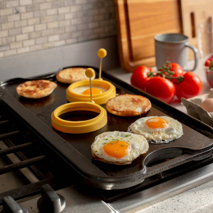 Pre-seasoned cast iron griddle with ribs on one side and flat surface on the other, cooking eggs and English muffins, ideal for Kitchen & Food, Cast Iron, USA Made, and Best Sellers collections.
