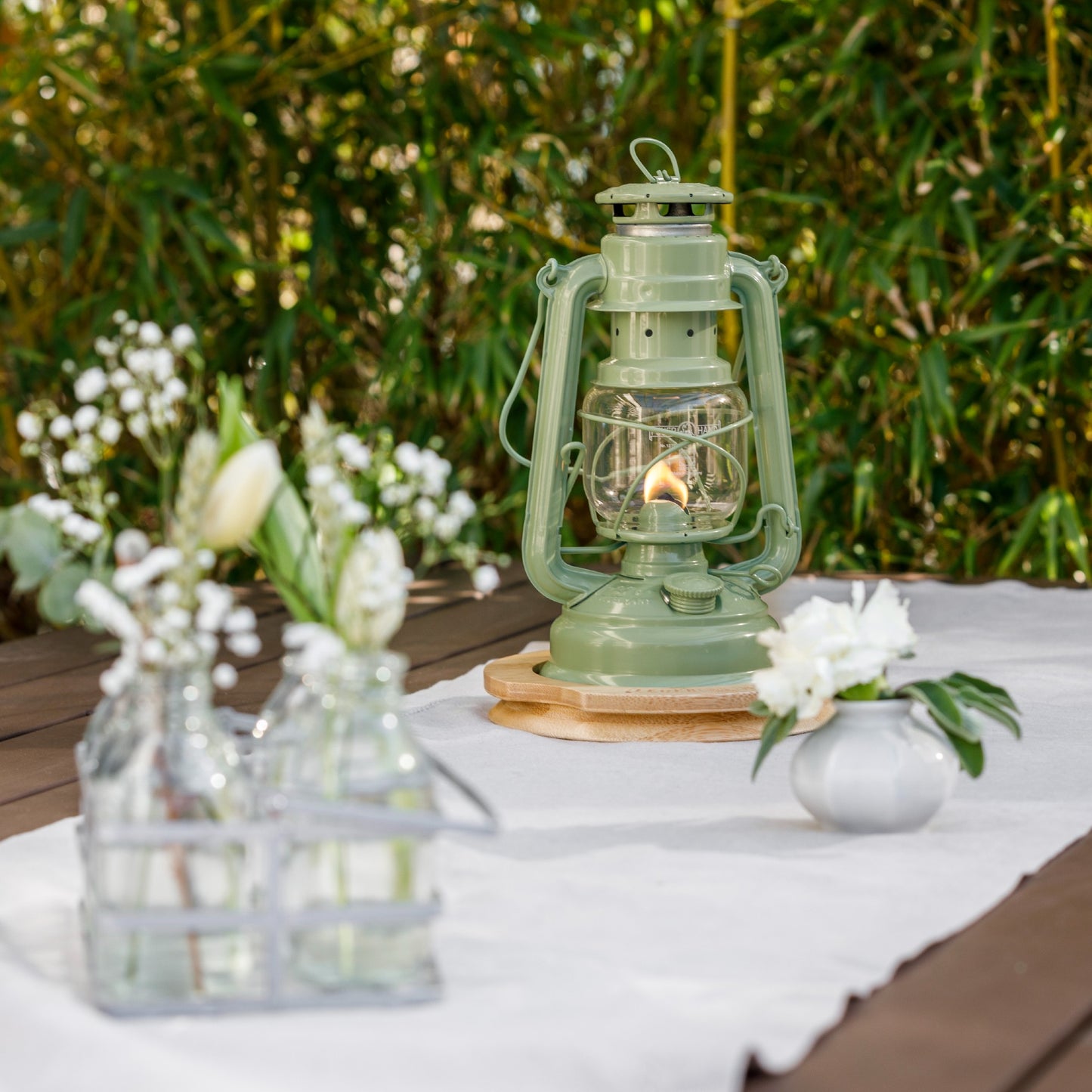 Handcrafted green galvanized oil lantern with thermal heat-resistant SUPRAX globe burning softly on an outdoor wooden table, ideal for Lamps & Lighting, Camping, and Emergency Supplies collections.