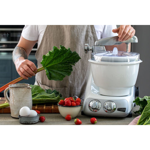 Person preparing fresh rhubarb and strawberries next to a white ice cream mixer attachment on a stand mixer, surrounded by eggs and a rustic ceramic pitcher, ideal for Kitchen & Food and Specialty Equipment collections.
