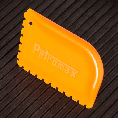 Bright orange pan scraper with notched edges designed for gentle cleaning of cast iron cookware, featured in Kitchen & Food, Cookware, Cast Iron, Best Sellers, and Promo Eligible collections.