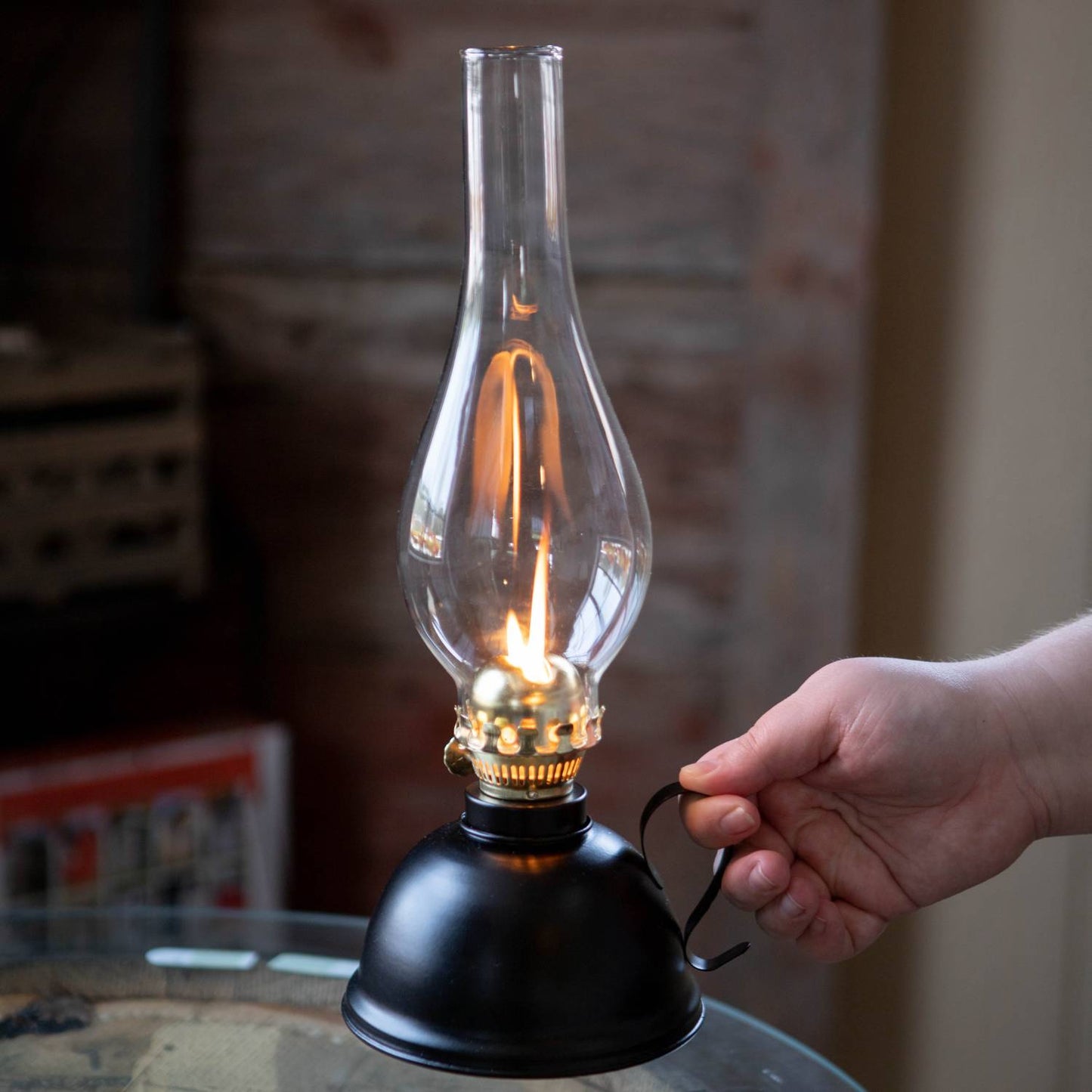 Handcrafted vintage-style oil lamp with black steel font and curved handle, lit flame under clear glass chimney, ideal for Farm, Garden & Tool and Emergency Supplies collections.