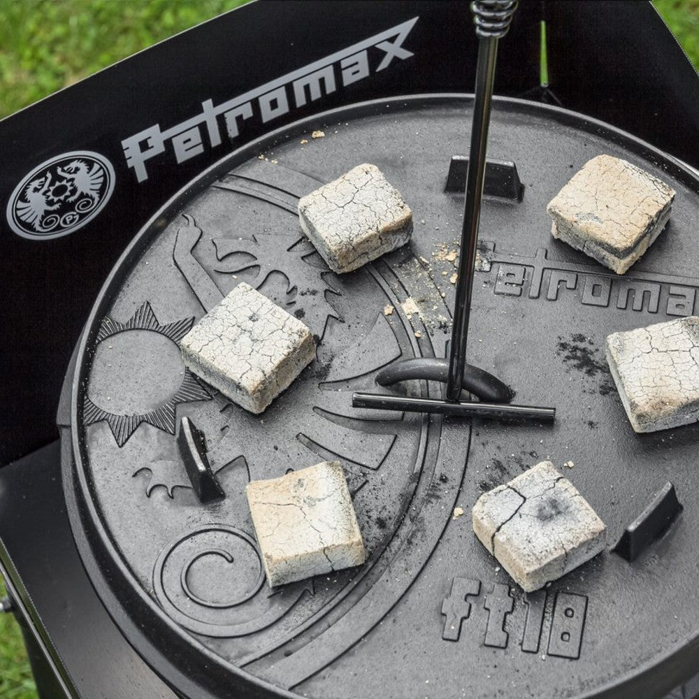 Close-up of the embossed lid of a cast iron Dutch oven showing six square charcoal briquettes arranged around the Petromax logo, ideal for outdoor cooking in Kitchen & Food, Cookware, Cast Iron, Best Sellers, Promo Eligible collections.