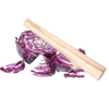 Smooth natural wood stomper resting on freshly cut purple cabbage wedges, designed for tamping down fermenting foods in kitchen, food preservation, and pickling tasks.