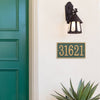 Green and gold rectangular custom address plaque displaying house number 31621 mounted on white exterior wall beneath a rustic black lantern light, near green front door, handcrafted in the USA, suitable for Home & Decor, Household Helpers, Mailboxes and Address Signs, and Best Sellers collections.