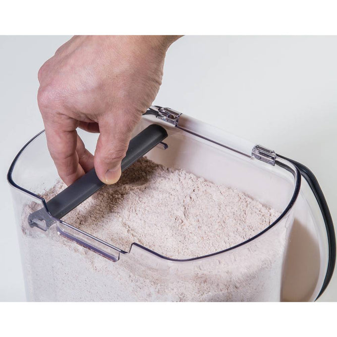 Hand lifting the black built-in leveler inside a clear airtight flour keeper filled with flour, designed for freshness and precise measuring, featured in Kitchen & Food, Storage and Serving, Best Sellers, and Promo Eligible collections.