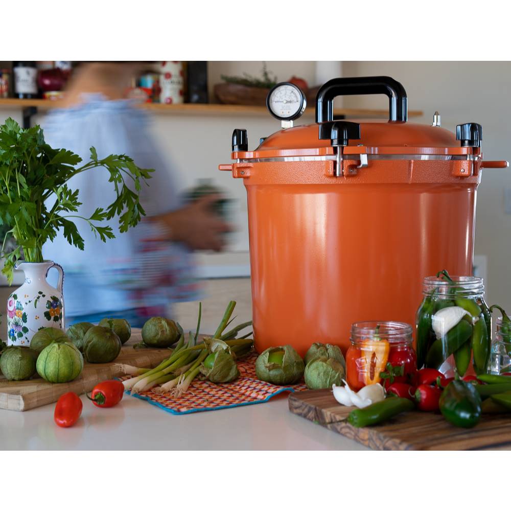 Bright orange 21.5-quart pressure canner with secure locking lid and pressure gauge, surrounded by fresh produce and jars for food preservation in Kitchen & Food and USA Made collections.
