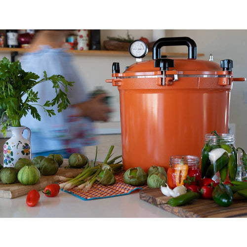 Bright orange 21.5-quart pressure canner with secure locking lid and pressure gauge, surrounded by fresh produce and jars for food preservation in Kitchen & Food and USA Made collections.