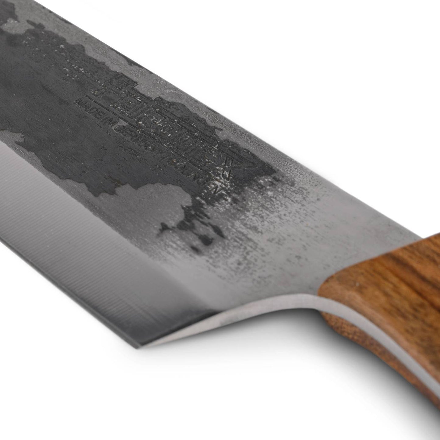 Close-up of a handcrafted chef's knife blade with a hammered textured finish and sharp edge, featuring a smooth walnut handle, ideal for outdoor cooking and food preparation collections.