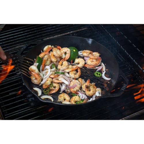 Handcrafted seasoned cast iron grill basket with dual handles cooking shrimp, sliced onions, green pepper, and zucchini over open flame, featured in Kitchen & Food, Cast Iron, Grilling, and Best Sellers collections.