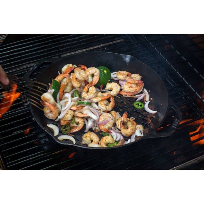 Handcrafted seasoned cast iron grill basket with dual handles cooking shrimp, sliced onions, green pepper, and zucchini over open flame, featured in Kitchen & Food, Cast Iron, Grilling, and Best Sellers collections.