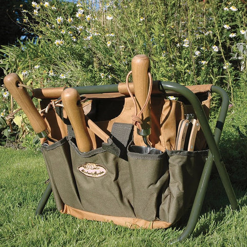 Compact green canvas garden stool with wooden-handled tools in side pockets, designed for comfortable outdoor use and organized gardening, featured in Farm, Garden & Tool collections.
