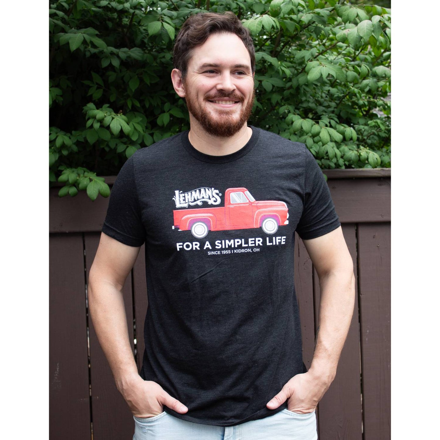 Adult wearing a soft charcoal t-shirt featuring a vintage red truck graphic with Lehman's logo and "For a Simpler Life" text, ideal for Health & Wellness and Clothing collections.