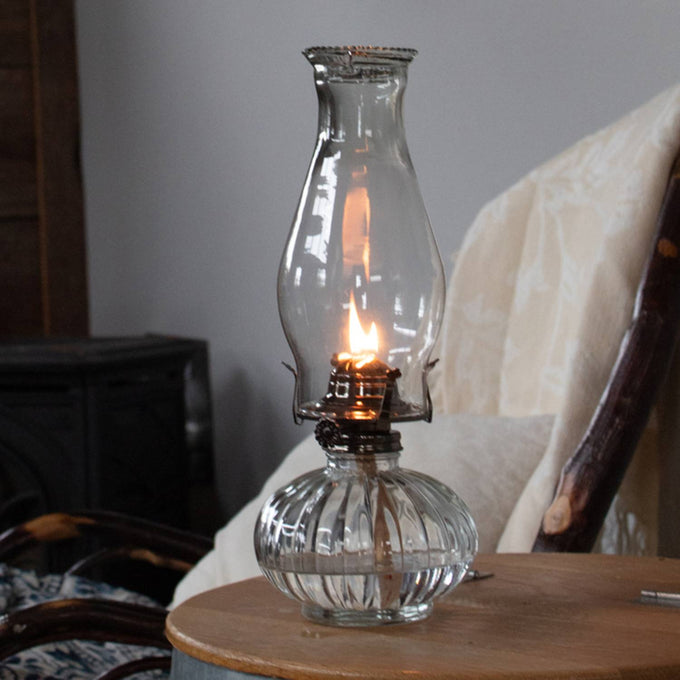 Handcrafted clear glass oil lamp with an elegant curved chimney and fluted base, offering affordable, non-electric lighting ideal for table lamps, emergency supplies, and farm use.