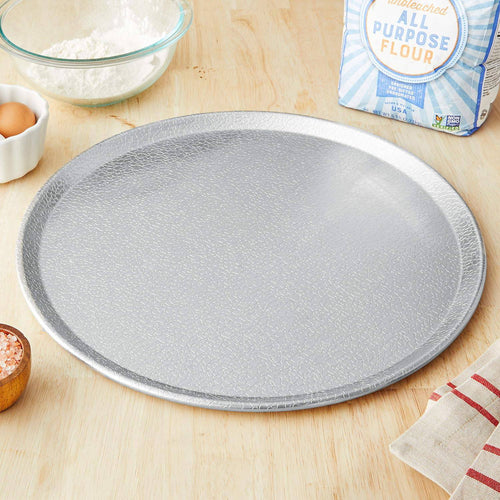Heavy-gauge recyclable aluminum pizza pan with raised edge and pebble texture for airflow, designed for kitchen and cookware use in baking and pizza preparation.